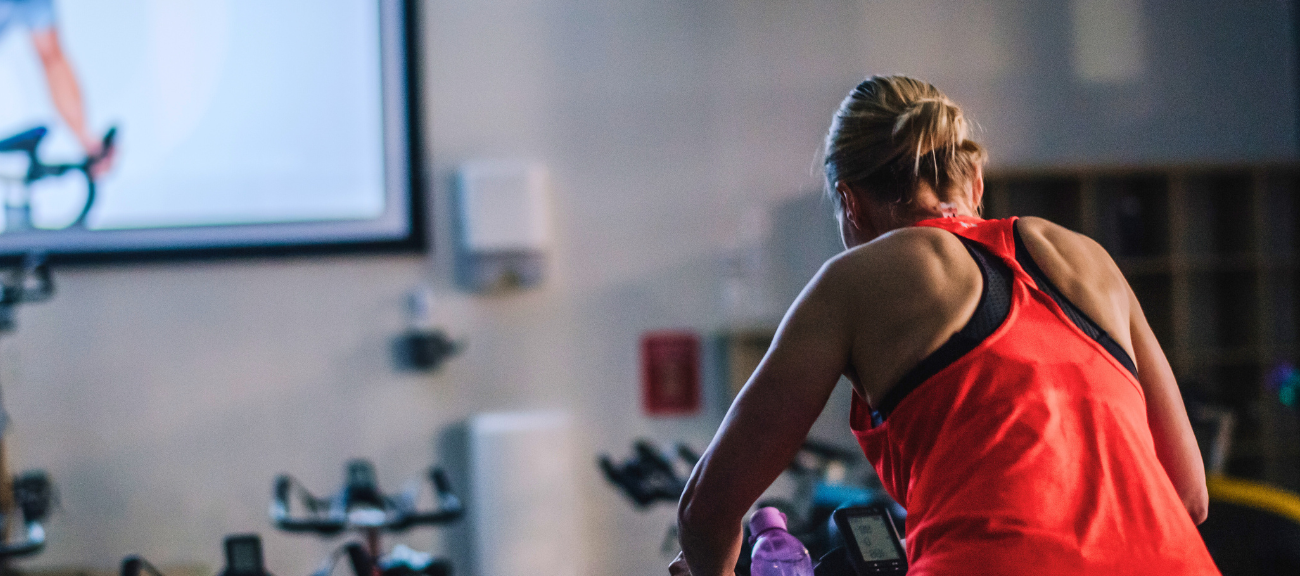 Women riding on indoor bike in red singlet