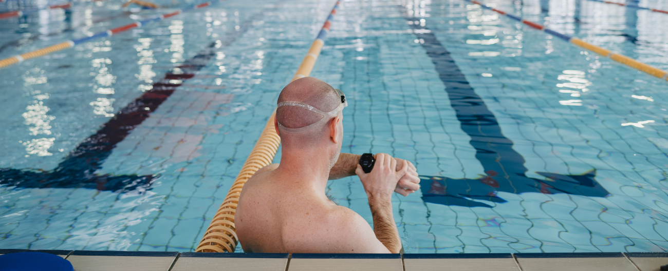 Picture of the back of a man's head. Man is checking his watch in the 50m pool at Aqualink Nunawading