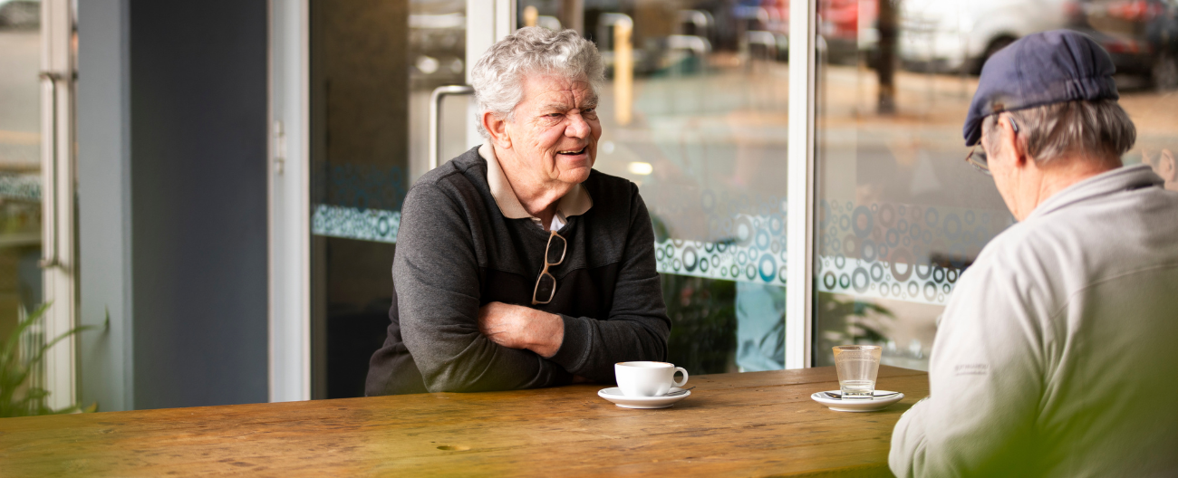 Image of two older men having a coffee outside Aqualink Box Hill