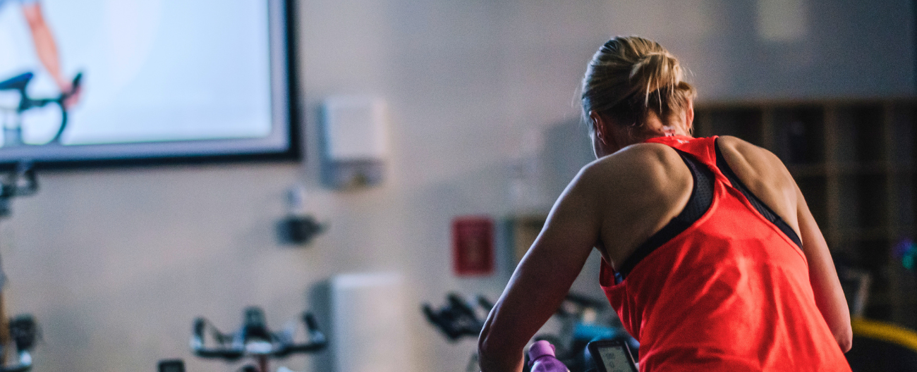 Women riding on indoor bike in red singlet