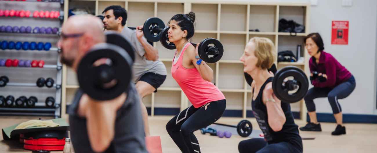 LesMills PUMP class, picture of 5 people doing a squat with a weighted bar bell on their shoulders